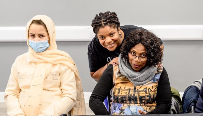 A shot of three women supported by charity Phoebe in Ipswich. Two are sitting down with another leaning over and smiling. They are all facing the camera