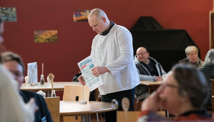 A man places a menu on a cafe table in Cafe 16 in Newcastle Cathedral