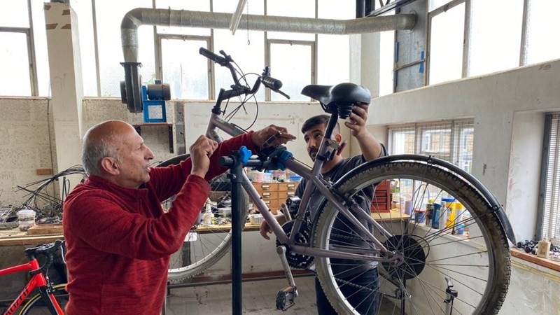 Two men lifting up a bike