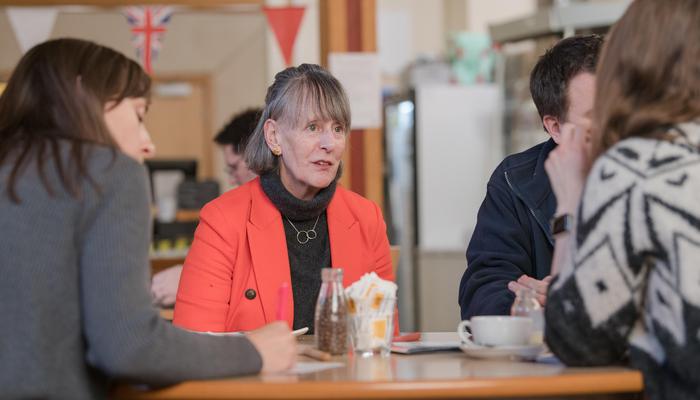 Fiona, CEO of The Oswin Project, sits at a table and talks to a group