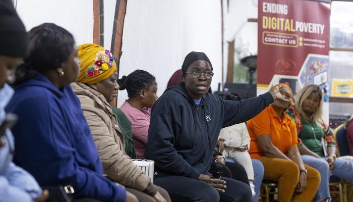 A group of Black women listen to a woman talking at WODIN