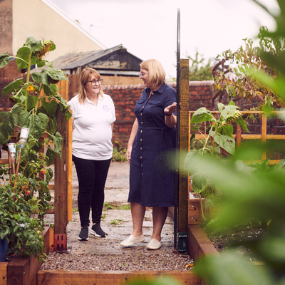 Director Caroline Johnson and Grant Manager, Rachel Marshall, are walking through a gate, looking at each other and talking