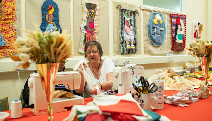 Women help each other with sewing at the Mojatu Foundation