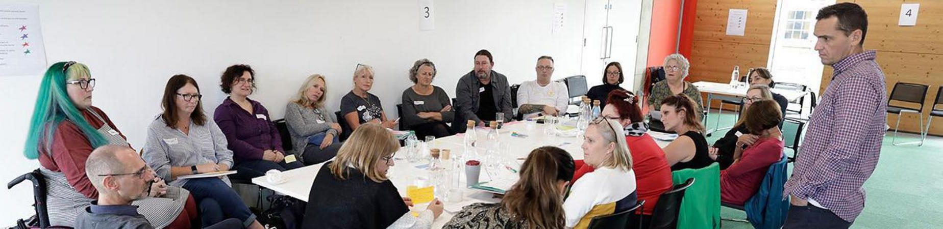 A gathering of people around a table representing their communities