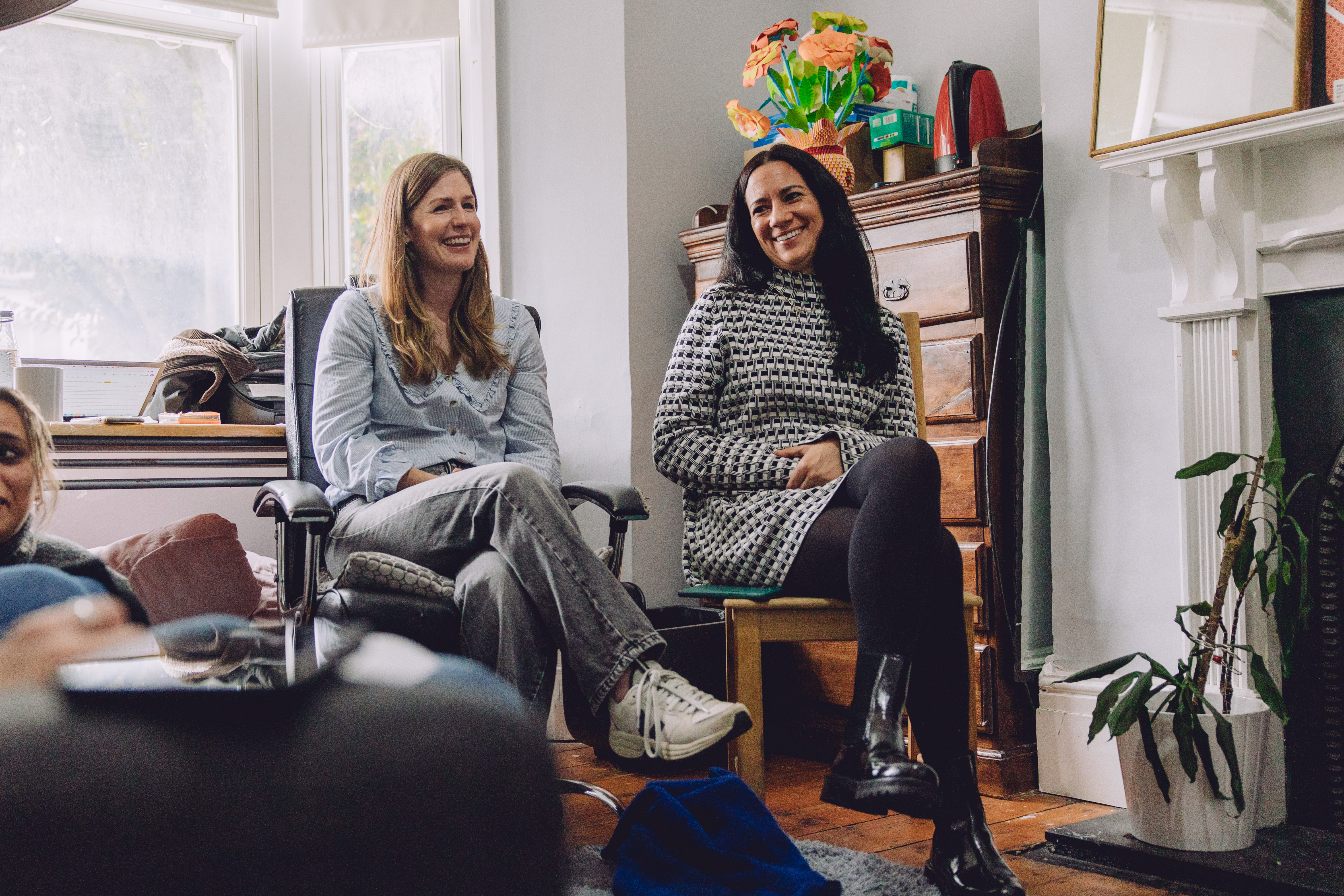 Staff at Ella's smiling in conversation with a group of survivors